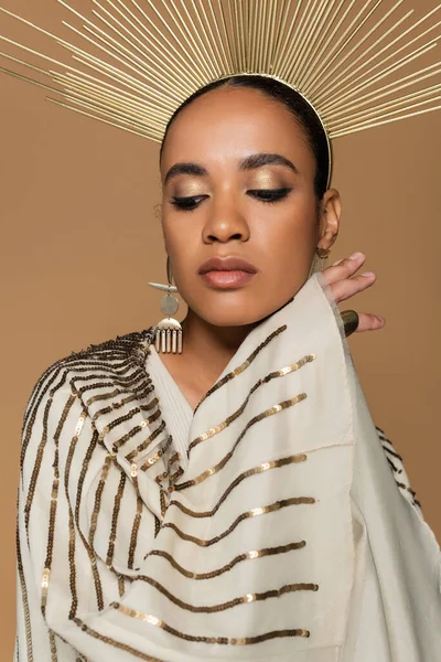 Selbstbewusste afrikanisch-amerikanische Frau in glänzendem Schal und goldener Krone posiert isoliert auf beige — Stockfoto