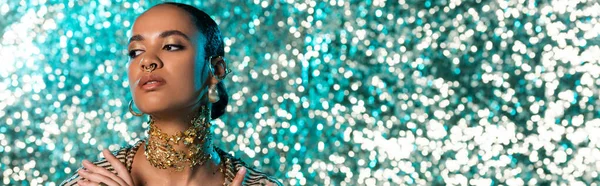 Проколота афроамериканська жінка з золотом на шиї дивиться на блискучий синій фон, банер — стокове фото