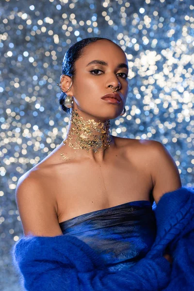 Модная африканская модель в мягком голубом свитере и золотой фольге на шее на сверкающем фоне — стоковое фото