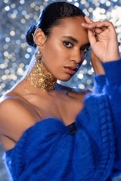 Retrato de mulher americana africana na moda com acessórios dourados olhando para a câmera no fundo espumante — Fotografia de Stock
