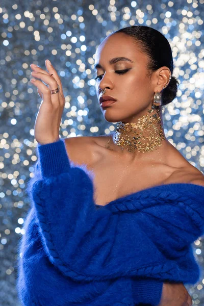 Donna afro-americana alla moda con lamina d'oro sul collo in posa su sfondo scintillante — Foto stock
