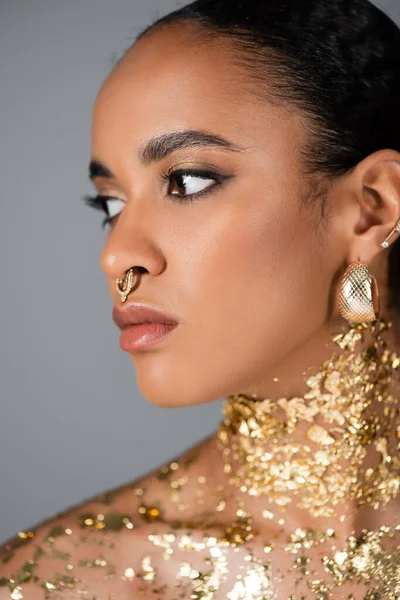 Porträt eines jungen afrikanisch-amerikanischen Modells mit goldener Folie am Hals, das isoliert auf grau wegschaut — Stockfoto
