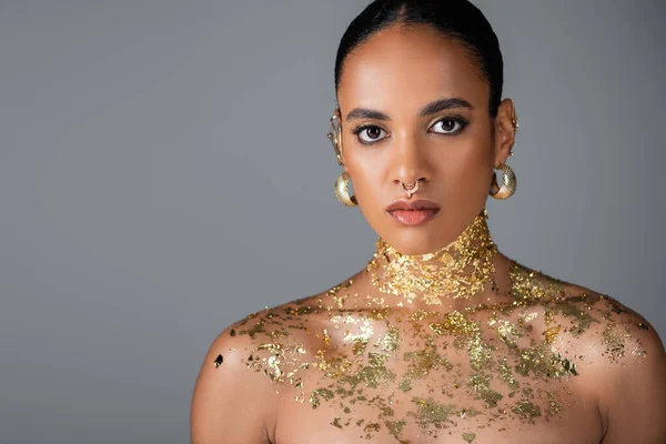 Afroamerikanisches Modell mit goldenen Accessoires und Folie auf der Brust isoliert auf grau — Stockfoto