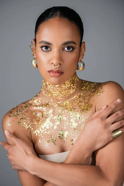 Modelo afroamericano de moda con lámina dorada en el cuello posando aislado en gris - foto de stock