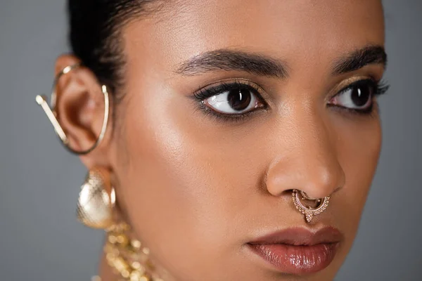 Nahaufnahme einer afrikanisch-amerikanischen Frau mit goldenem Piercing, die isoliert auf grau wegschaut — Stockfoto