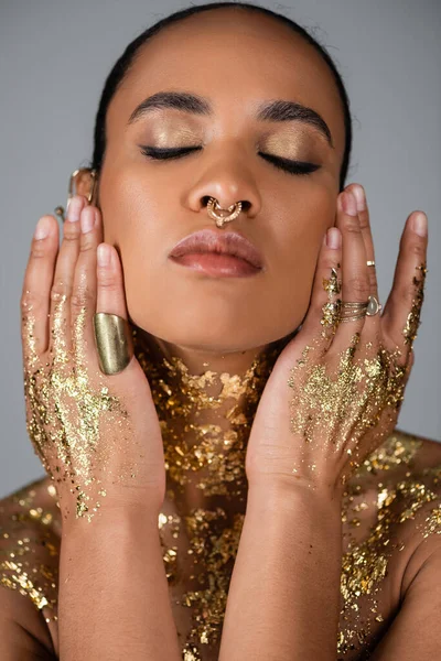 Portrait de femme afro-américaine élégante avec feuille d'or sur la poitrine et les mains isolées sur le gris — Photo de stock