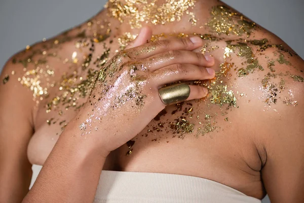 Cropped view of young african american woman touching golden foil on body isolated on grey — Stock Photo