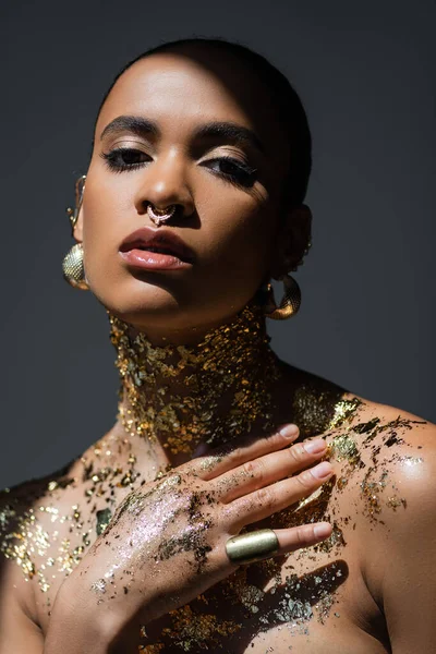 Модна афроамериканка з золотими аксесуарами і фольгою на тілі ізольована на сірому зі світлом — стокове фото