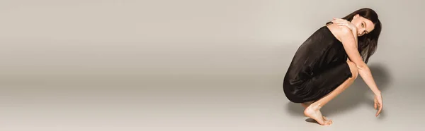 Молода босоніжка з вітіліго позує в сукні на сірому фоні, банер — стокове фото