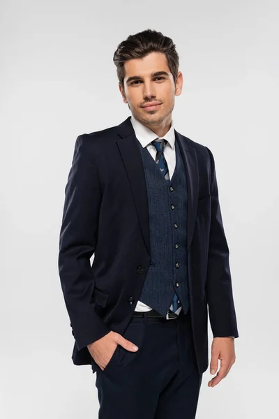 Уверенный в себе бизнесмен в костюме, стоящий с рукой в кармане, изолированный на сером — стоковое фото
