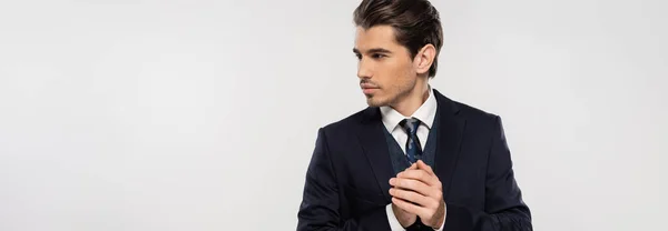 Gut aussehender und junger Geschäftsmann im Anzug, der isoliert auf grauem Banner wegschaut — Stockfoto