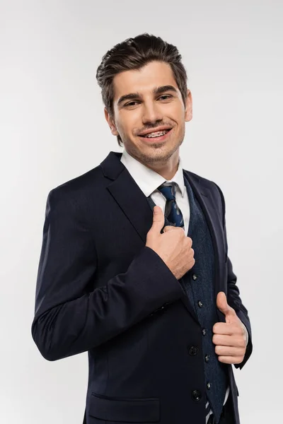 Allegro e giovane uomo d'affari con bretelle di regolazione cravatta isolato su grigio — Foto stock