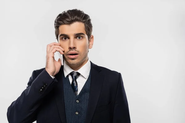 Shocked businessman in suit talking on smartphone isolated on grey — Stock Photo