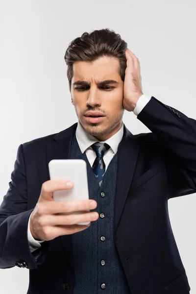 Uomo d'affari preoccupato in tuta messaggistica su smartphone isolato su grigio — Foto stock