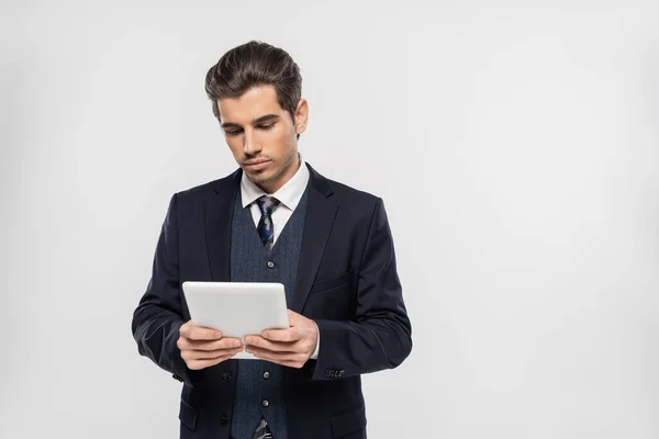 Homme d'affaires réussi en costume en utilisant tablette numérique isolé sur gris — Photo de stock