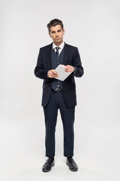 Pleine longueur de succès homme d'affaires en costume tenant tablette numérique sur gris — Photo de stock