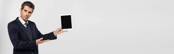 Junger Geschäftsmann im Anzug mit digitalem Tablet und leerem Bildschirm auf grauem Banner — Stock Photo