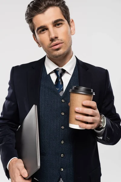 Молодий бізнесмен тримає паперову чашку і ноутбук ізольовано на сірому — стокове фото