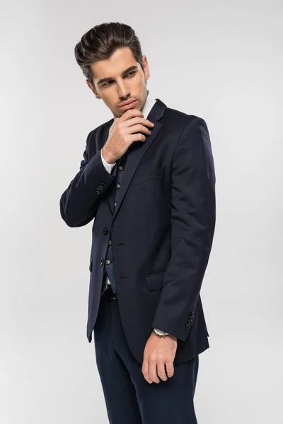 Hombre de negocios guapo y joven en ropa formal mirando hacia otro lado aislado en gris - foto de stock