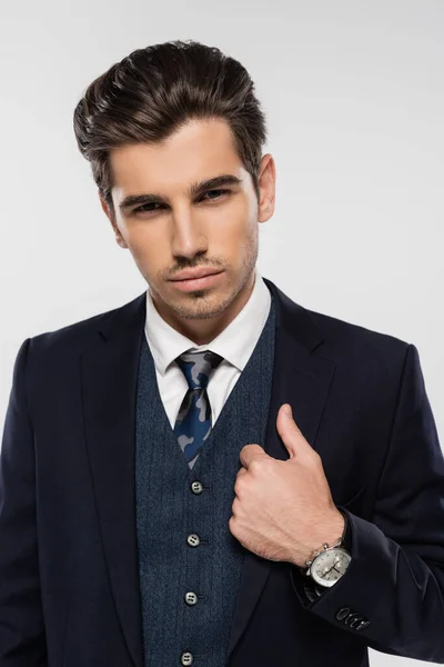 Retrato de hombre de negocios en ropa formal ajustando blazer de pie aislado en gris - foto de stock