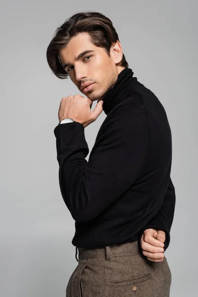 Junger gut aussehender Mann posiert im trendigen Rollkragen isoliert auf grau — Stockfoto