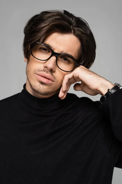 Portrait of good looking man in black turtleneck and eyeglasses posing isolated on grey — Stock Photo