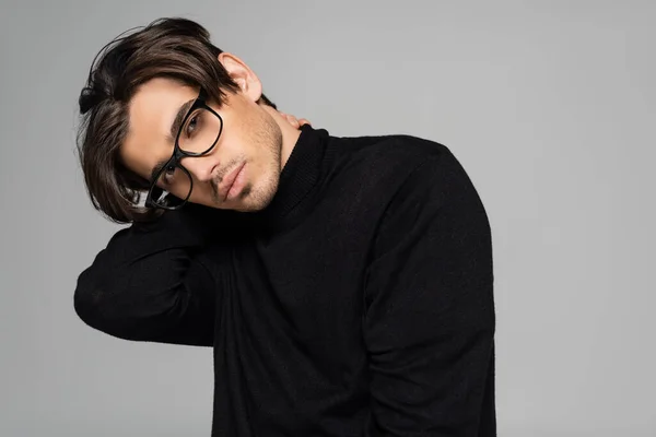 Brunette man in black turtleneck and eyeglasses looking at camera isolated on grey — Stock Photo
