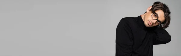 Brunetta uomo in dolcevita nero e occhiali guardando la fotocamera isolata su grigio, banner — Foto stock