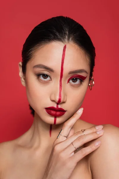 Porträt einer brünetten asiatischen Frau mit händennahem Gesicht und kreativem Gesicht, die isoliert auf rot in die Kamera blickt — Stockfoto