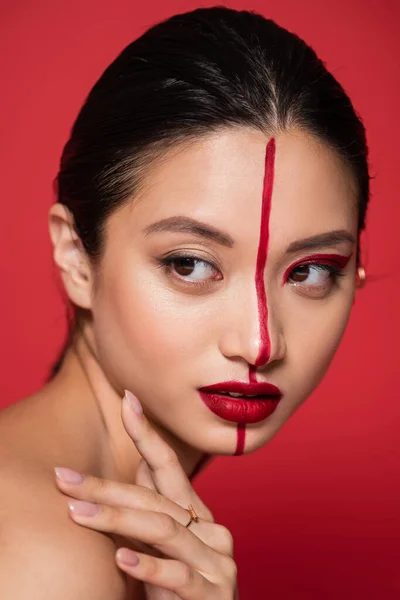 Porträt einer asiatischen Frau mit leuchtendem künstlerischem Gesicht, die isoliert auf Rot wegschaut — Stockfoto