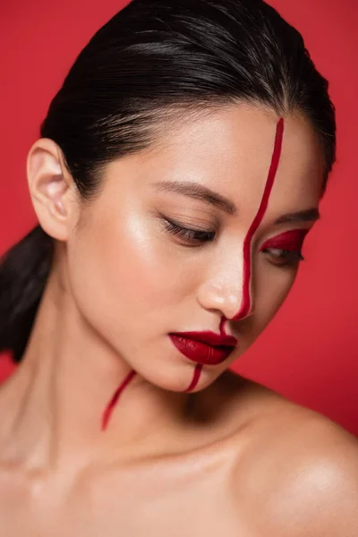 Портрет брюнетки азіатки з креативним оком і голим плечем позує ізольовано на червоному — стокове фото
