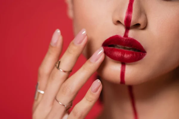Visão parcial da mulher tocando lábios brilhantes na face dividida com a linha isolada no vermelho — Fotografia de Stock