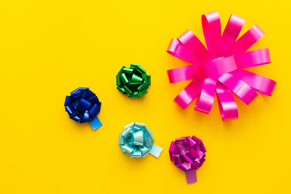 Top view of shiny gift bows on yellow background — Stock Photo