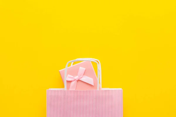 Вид сверху розовой подарочной коробки и сумки для покупок на желтом фоне — стоковое фото