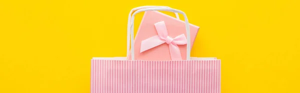 Top view of pink present and striped shopping bag on yellow background, banner — Stock Photo