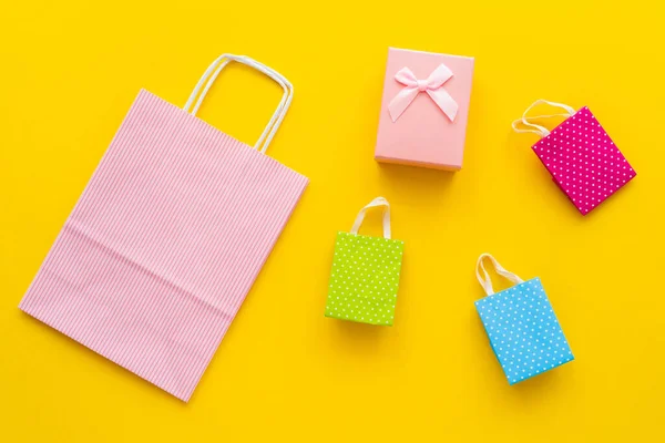 Top view of gift box and shopping bags on yellow background — Stock Photo
