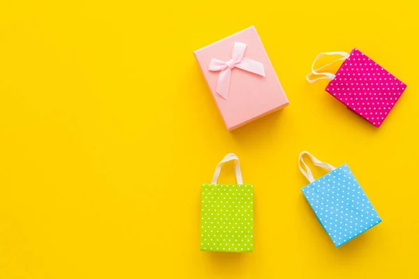 Вид сверху на розовую подарочную коробку и небольшие сумки на желтом фоне — Stock Photo