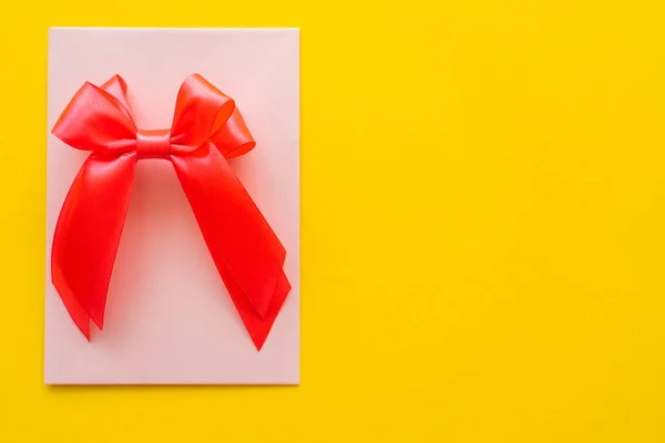 Top view of bow on greeting card on yellow background — Stock Photo