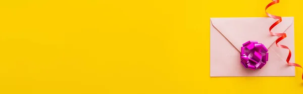 Vue du dessus de serpentine sur enveloppe avec noeud cadeau sur fond jaune, bannière — Photo de stock