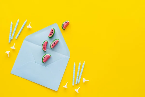 Top view of candies on envelope near festive candles on yellow background — Stock Photo