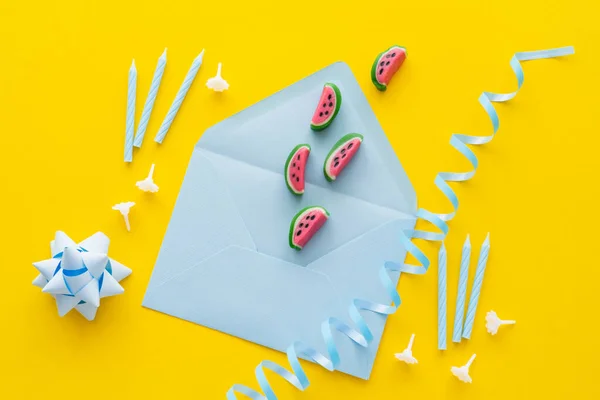 Верхний вид сладостей на конверте возле голубой змеи и праздничные свечи на желтом фоне — стоковое фото