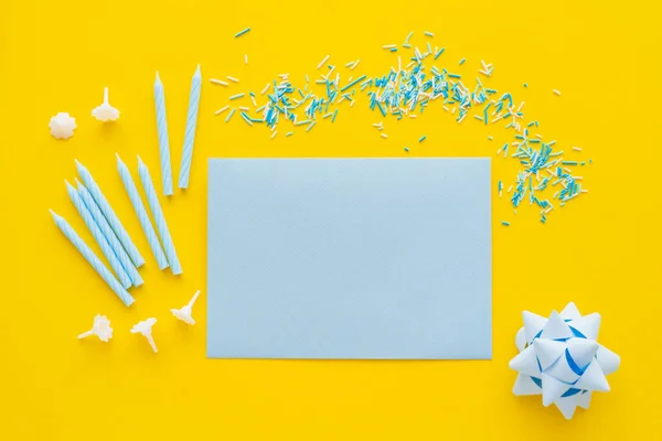 Top view of empty greeting card near candles and blue sprinkles on yellow background — Stock Photo