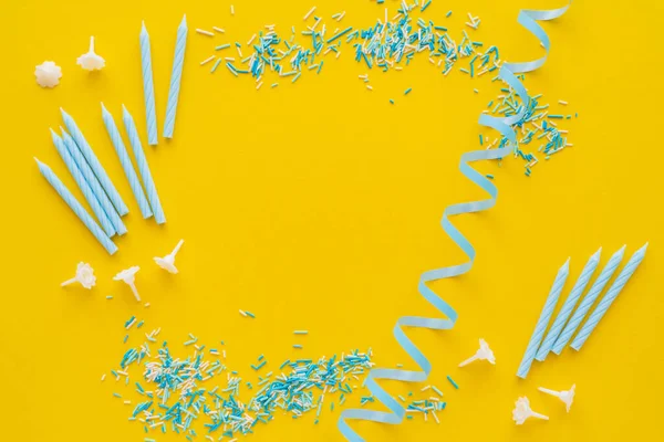 Vista dall'alto di candele vicino serpentina blu e spruzzi su sfondo giallo — Foto stock
