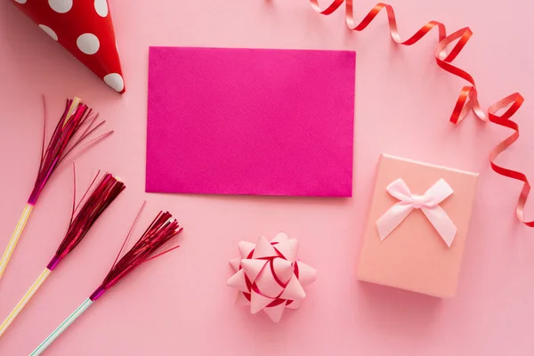 Top view of pink greeting card near gift box and serpentine on pink background — Stock Photo