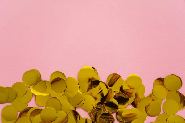 Vue du dessus des confettis dorés sur fond rose avec espace de copie — Photo de stock