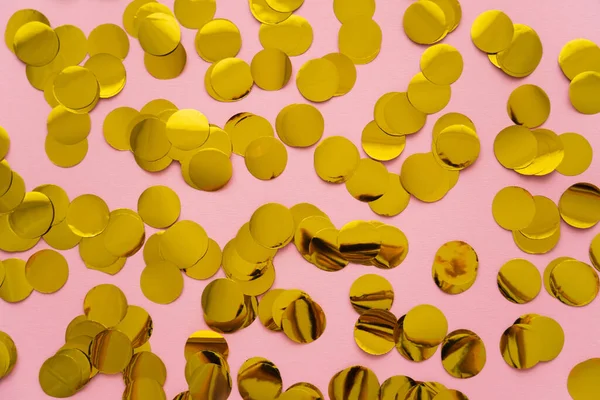 Vue du dessus des confettis dorés sur fond rose — Photo de stock