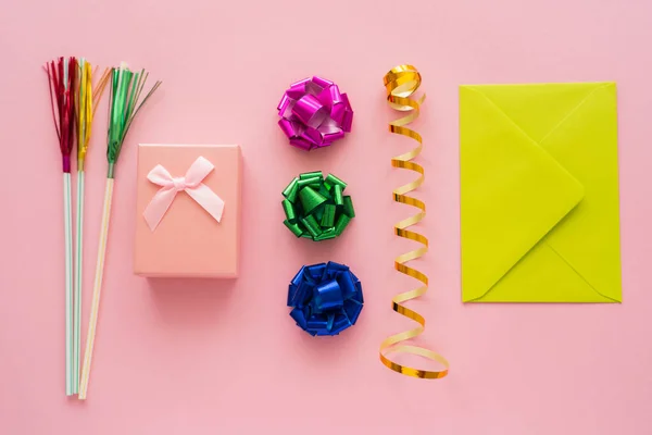 Top view of present near serpentine and envelope on pink background — Stock Photo
