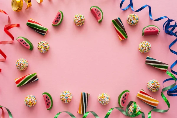 Puesta plana con caramelos de colores y serpentina sobre fondo rosa - foto de stock