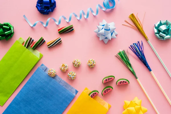 Draufsicht auf süße Bonbons in der Nähe von Trinkhalmen und Geschenkschleifen auf rosa Hintergrund — Stockfoto