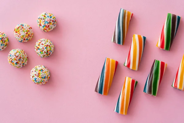 Flache Lage mit verschiedenen bunten Süßigkeiten auf rosa Hintergrund — Stockfoto